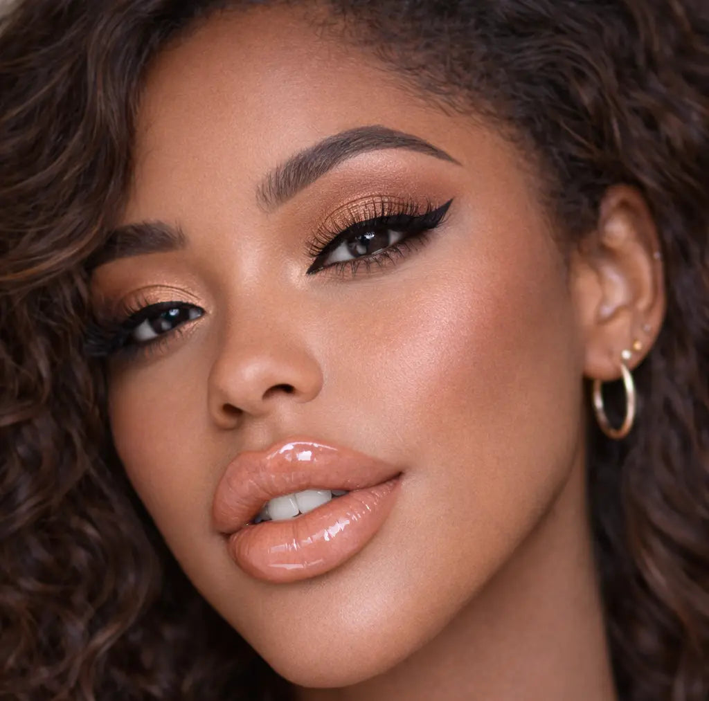 Close-up of a woman with curly hair wearing diamond glow peaches and cream lip gloss