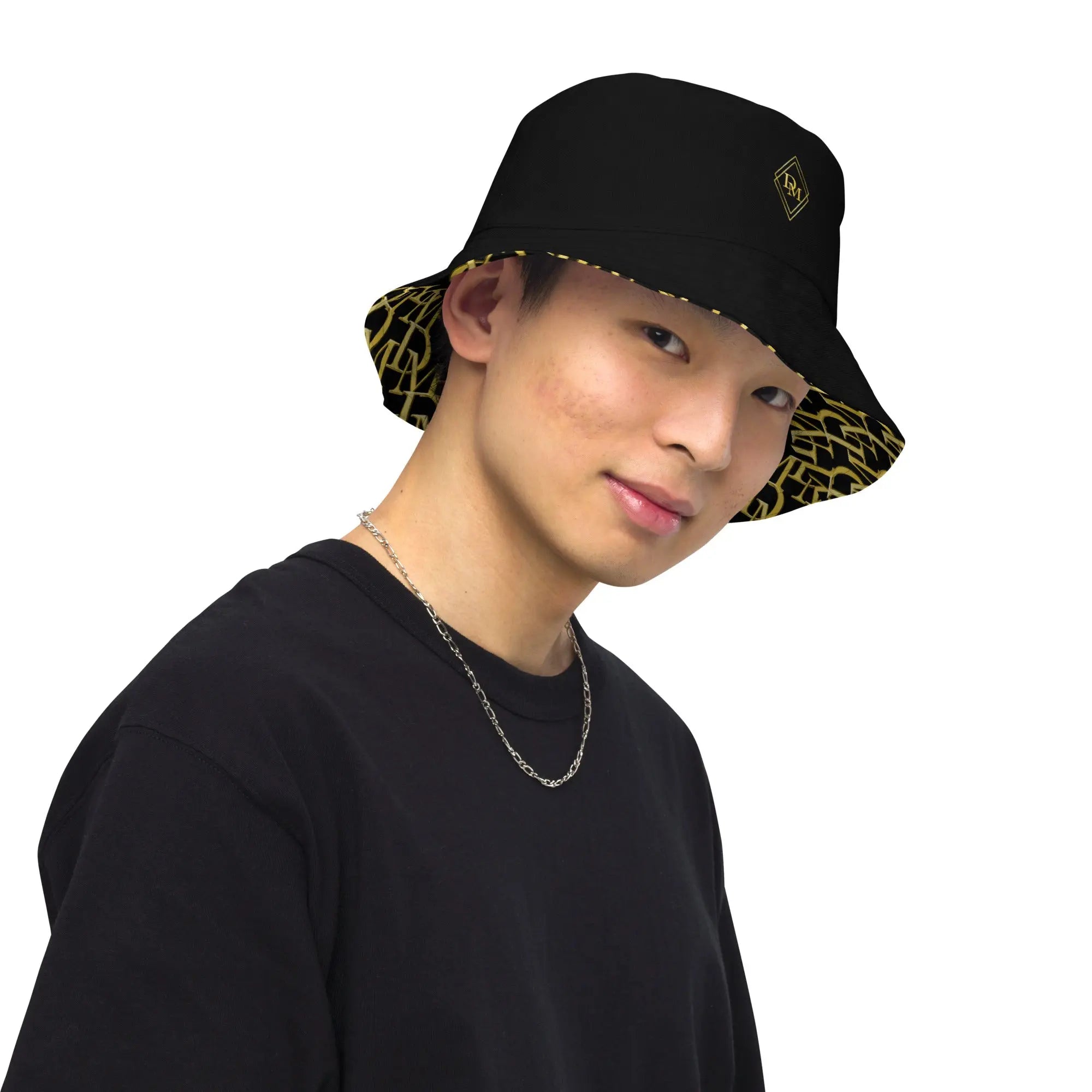 Person wearing a black bucket hat with a gold print interior on a white background