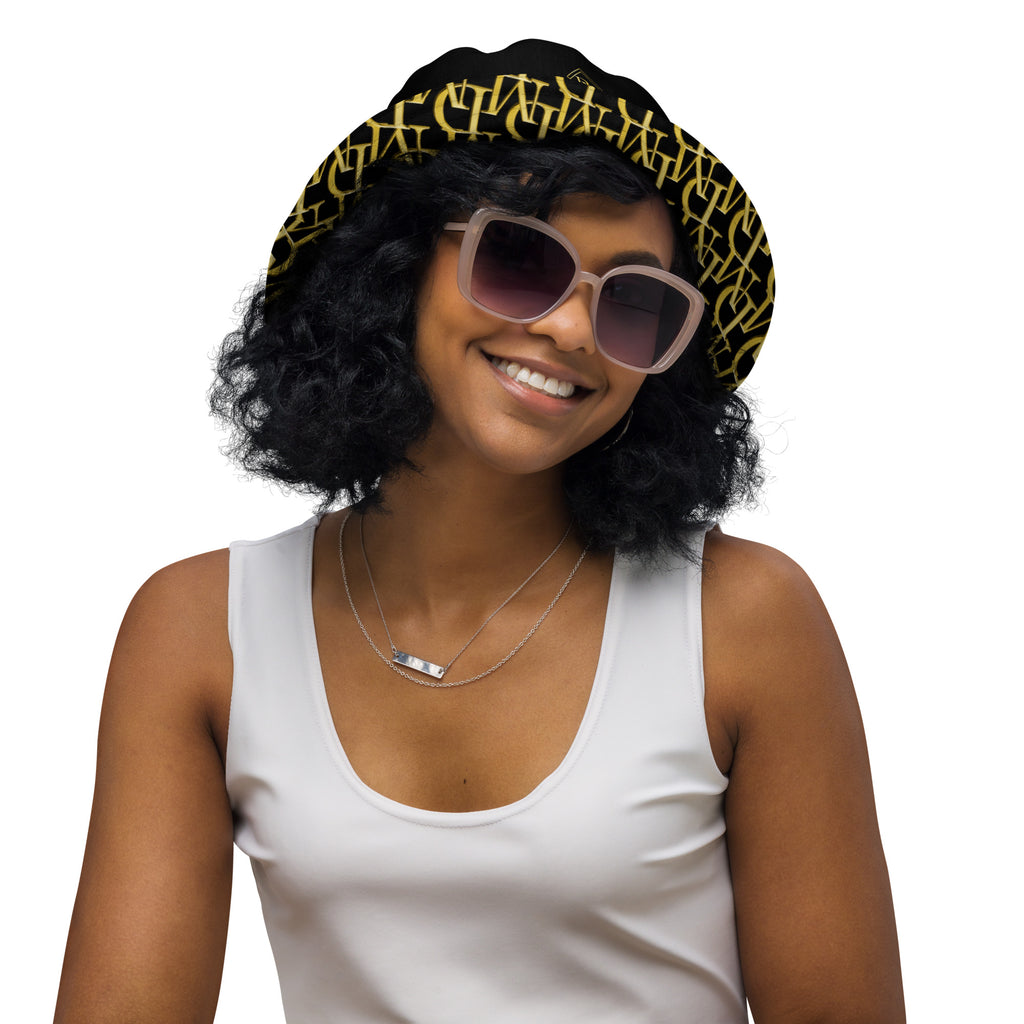 Woman wearing a black and gold patterned bucket hat and sunglasses on a white background