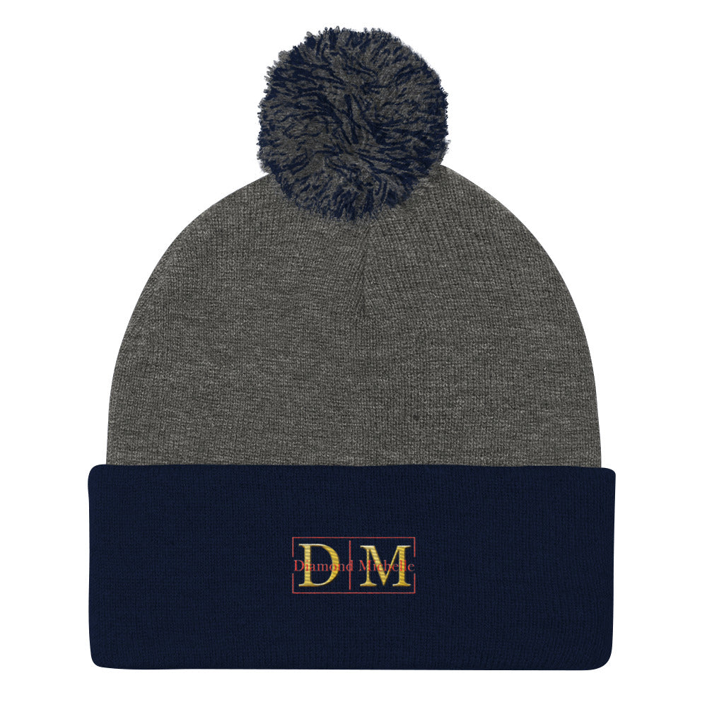 Flat front view of a dark heather and navy blue DM Pom-Pom Beanie on a white background