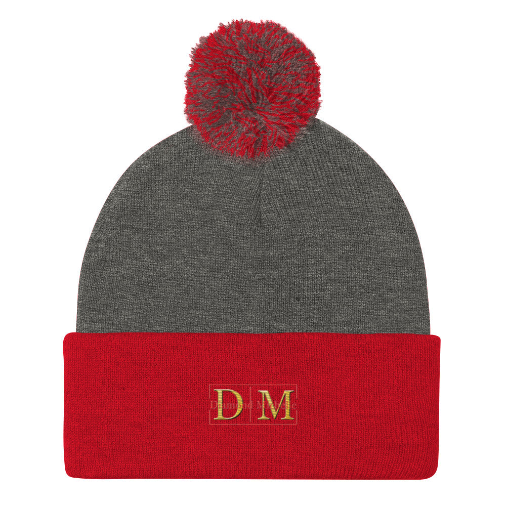 Flat front view of a dark heather and red DM Pom-Pom Beanie on a white background