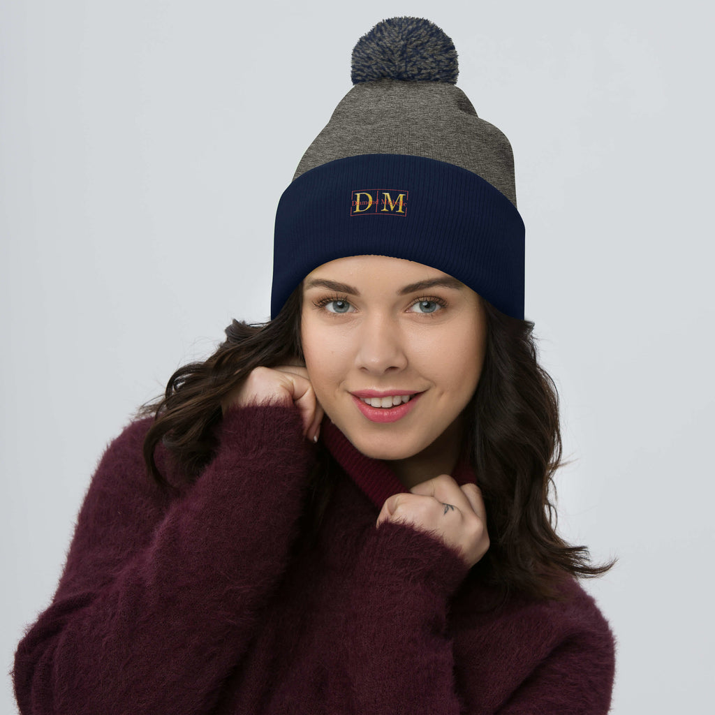 Woman wearing a dark heather grey and navy DM Pom-Pom Beanie front view