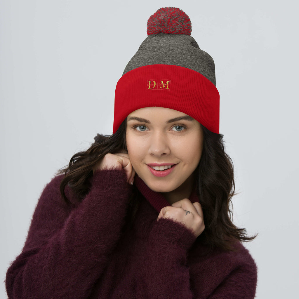Woman wearing a dark heather grey and red DM Pom-Pom Beanie front view