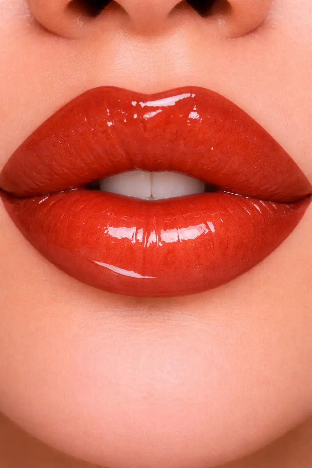 Close-up of glossy crimson red lip gloss on lips