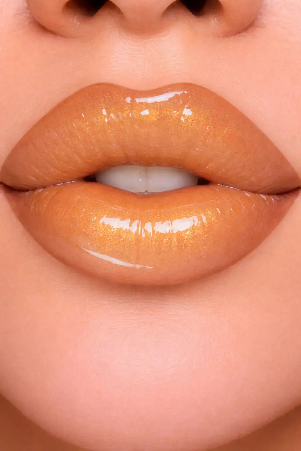 Close-up of glossy gold lips with a neutral background