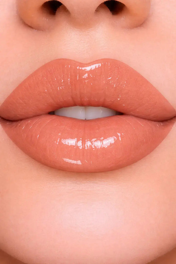 Close-up of glossy lips wearing nude color lip oil with a focus on texture and color.